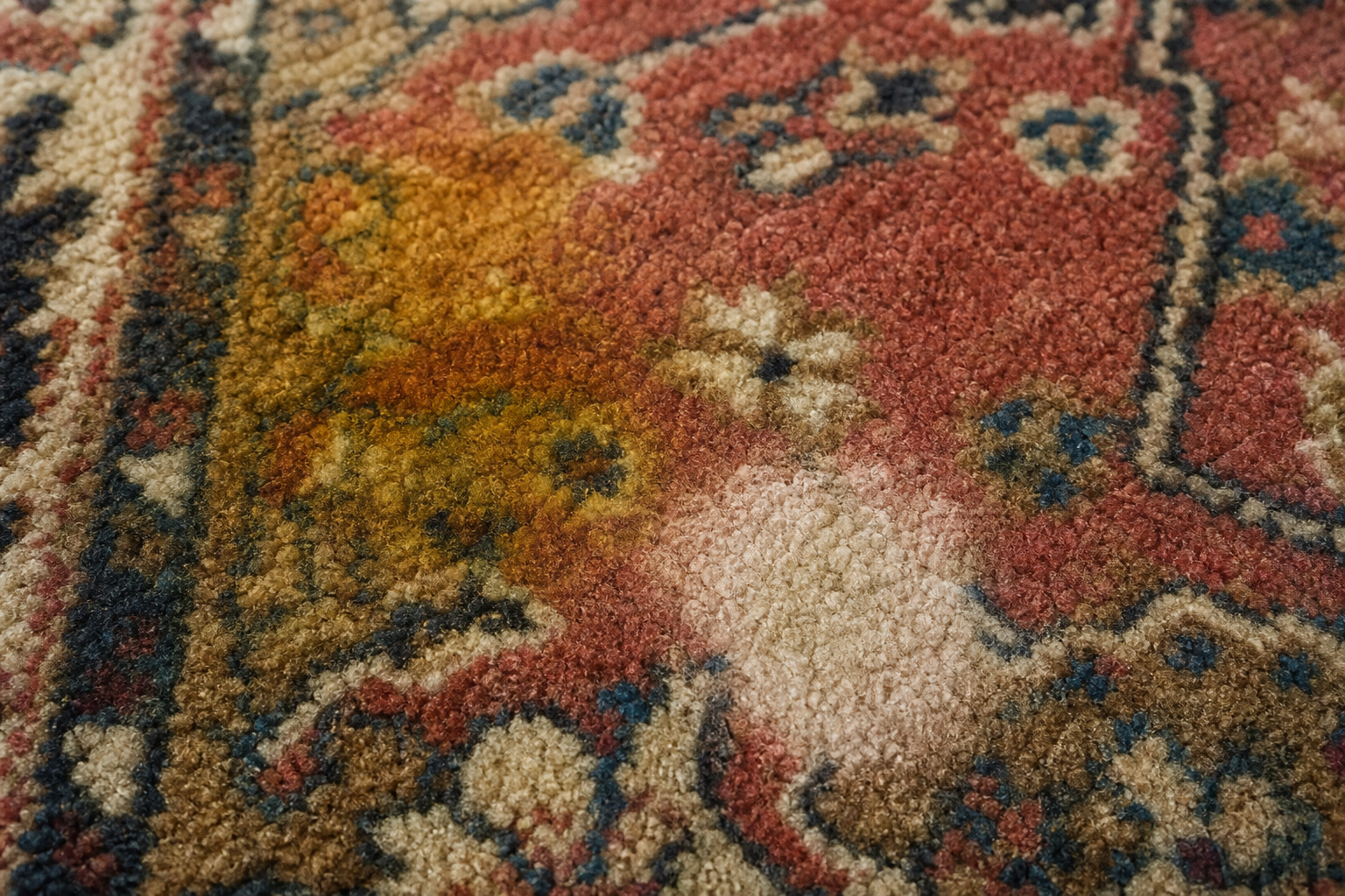 Macro close-up of rug fibers with a yellow pet stain and a bleached pale spot where dye was stripped