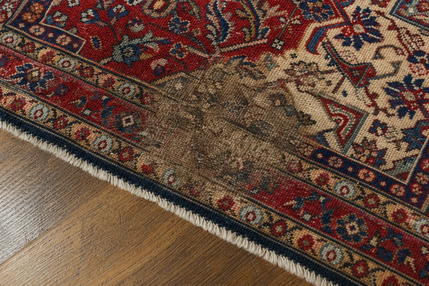 Close-up of a rug where a pet urine stain sits beside the still-fresh original colors